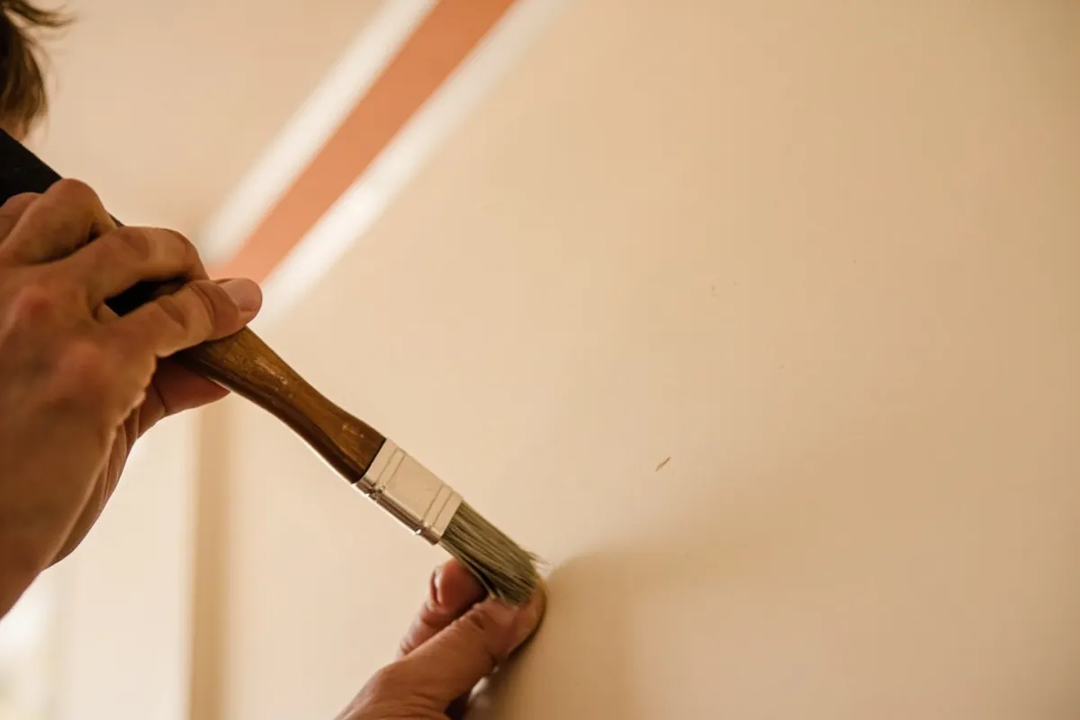 Painter cutting in clean lines along a ceiling and wall corner with a steady brush